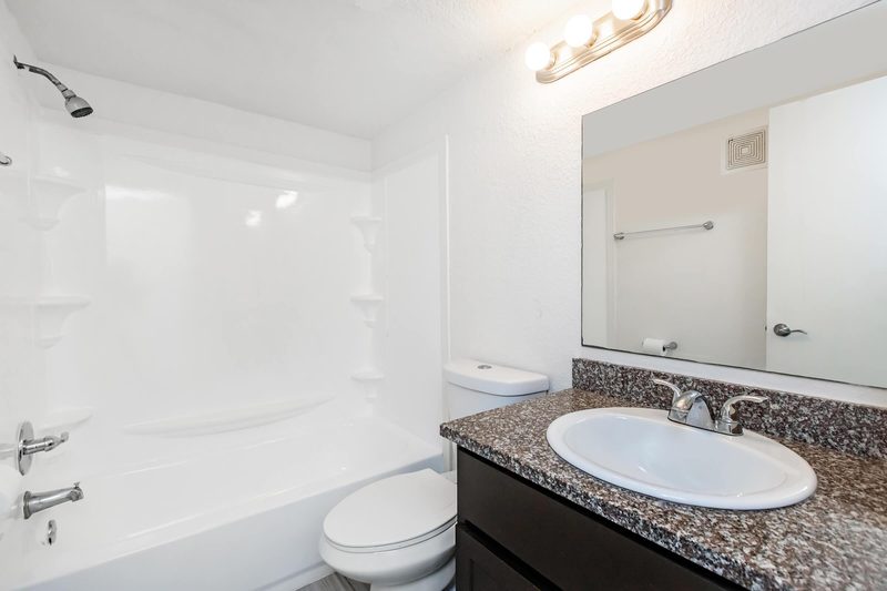 Full bathroom with granite-topped vanity and tub-shower